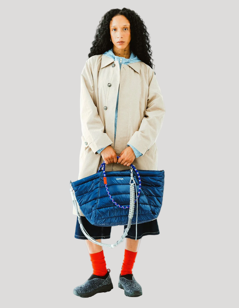 Person holding a blue quilted bag against a white background